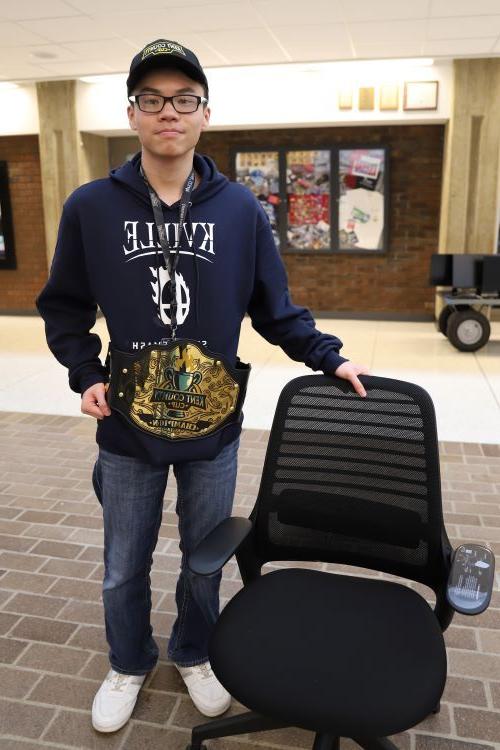 Kenny Nguyen, winner of esports competition, with championship belt and Steelcase gaming chair